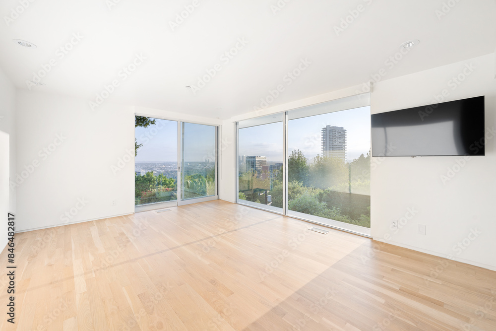 Fototapeta premium Empty room with white walls and panoramic city views through large windows