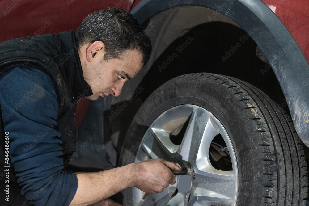 Mechanic with repairing car wheel in workshop. Hands replace tires on wheels. Mechanic with repairing car wheel in workshop. Hands replace tires on wheels.