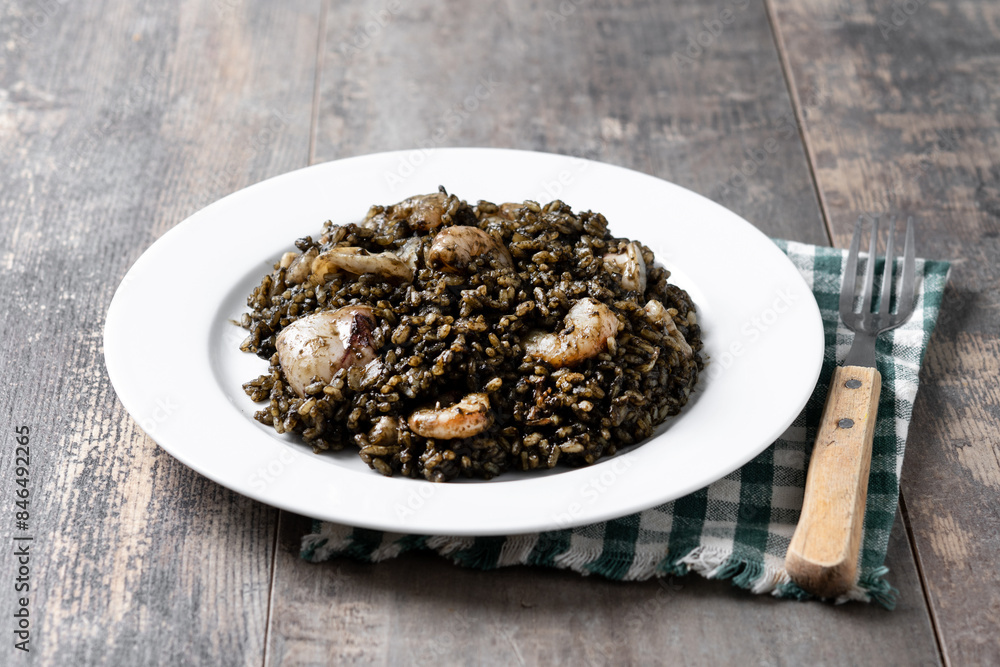 Black rice with seafood in plate on wooden table