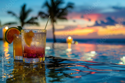 Tropical cocktails by the pool at sunset, with a serene ocean view and a vibrant sky backdrop.
