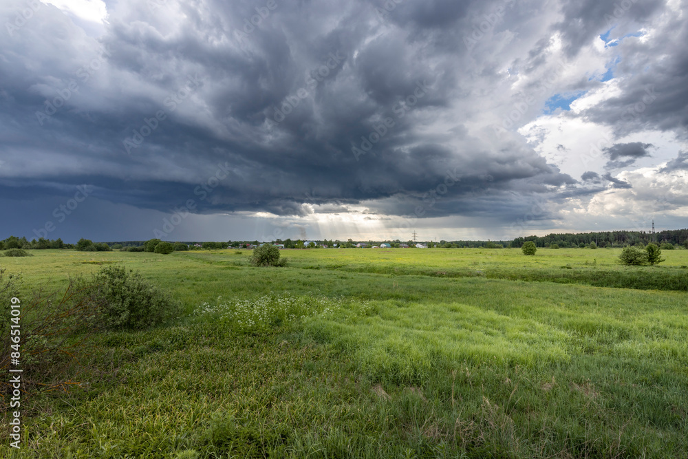 A vast, dramatic sky filled with dark storm clouds hangs over a lush, green field. The sunlight filters through the clouds, casting a soft glow on the landscape. A vast, dramatic sky filled with dark storm clouds hangs over a lush, green field. The sunlight filters through the clouds, casting a soft glow on the landscape.