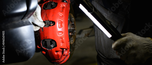 Mechanic holding lamp near disk brake in garage 