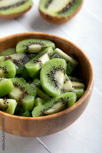 Kiwi and kiwi fruit salad in wooden bowl, selective focus