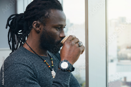 African business Man looking trough the window in the office, drinking coffee and thinking, close up photo