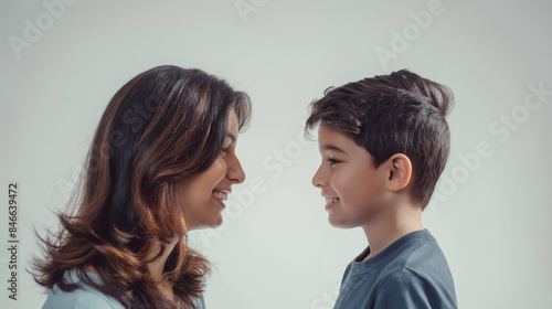 40 year old Latin mother standing to the side looking and smiling at her 7 year old Latin boy son, optimistic faces, in a large space with white background, optimistic faces, photo style