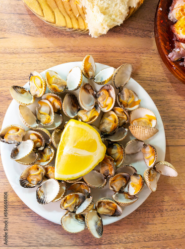 Wallpaper Mural A plate of freshly steamed cockles garnished with a slice of lemon, served on a wooden table with bread on the side. Torontodigital.ca