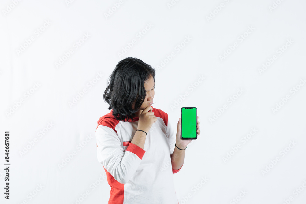 Young Asian woman looks happy in Indonesian Independence Day attire. woman shows her mobile phone with green screen suitable for advertising Young Asian woman looks happy in Indonesian Independence Day attire. woman shows her mobile phone with green screen suitable for advertising