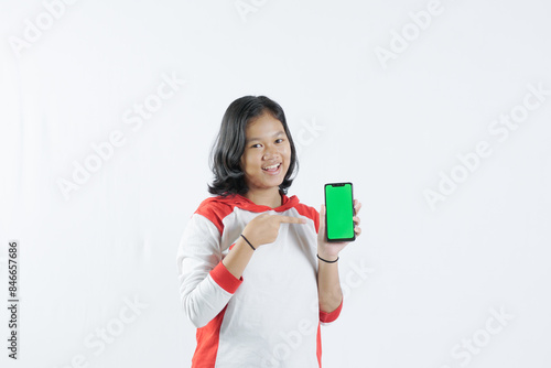 Young Asian woman looks happy in Indonesian Independence Day attire. woman shows her mobile phone with green screen suitable for advertising