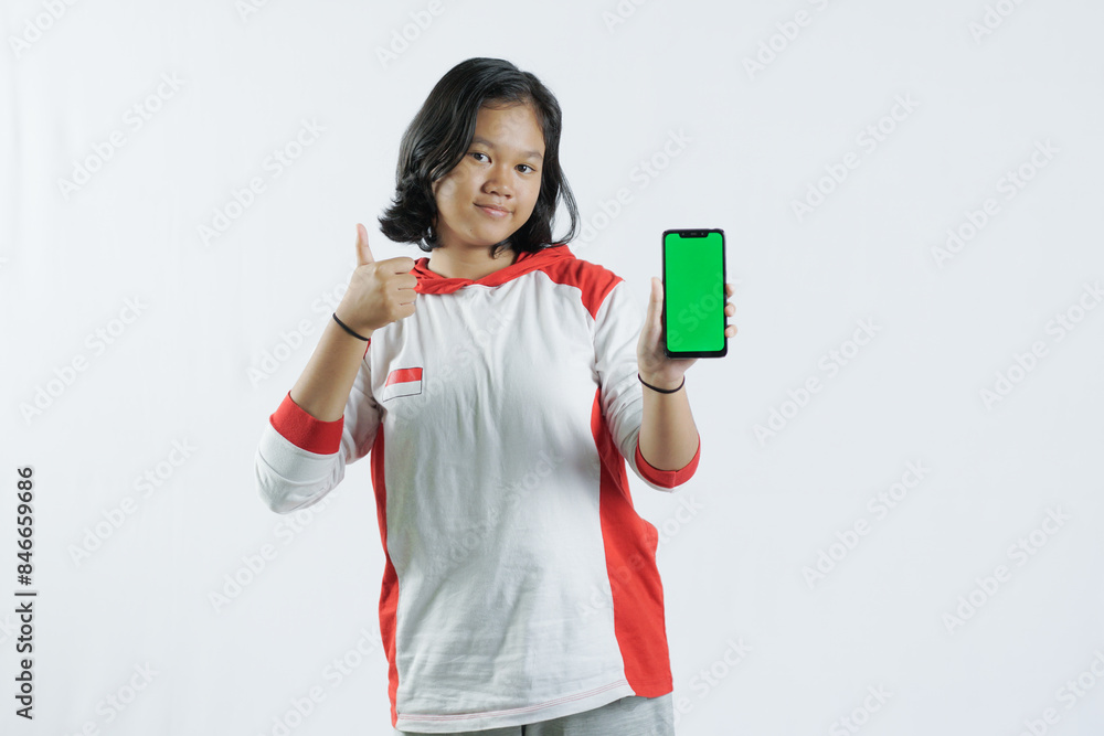 Young Asian woman looks happy in Indonesian Independence Day attire. woman shows her mobile phone with green screen suitable for advertising Young Asian woman looks happy in Indonesian Independence Day attire. woman shows her mobile phone with green screen suitable for advertising