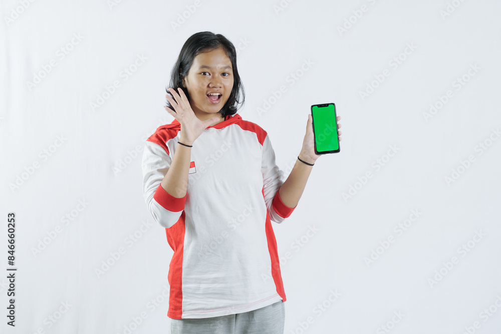 Young Asian woman looks happy in Indonesian Independence Day attire. woman shows her mobile phone with green screen suitable for advertising Young Asian woman looks happy in Indonesian Independence Day attire. woman shows her mobile phone with green screen suitable for advertising