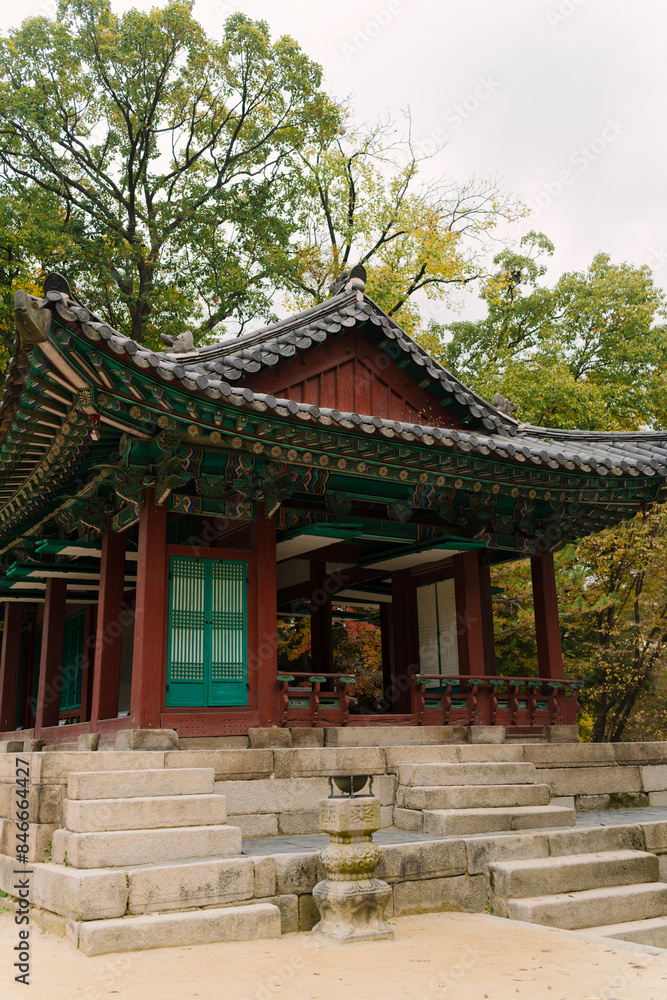 a traditional Korean pavilion with a tiled roof and green window details, set amidst lush trees in Changdeokgung Palace’s Biwon Garden, Seoul. a traditional Korean pavilion with a tiled roof and green window details, set amidst lush trees in Changdeokgung Palace’s Biwon Garden, Seoul.