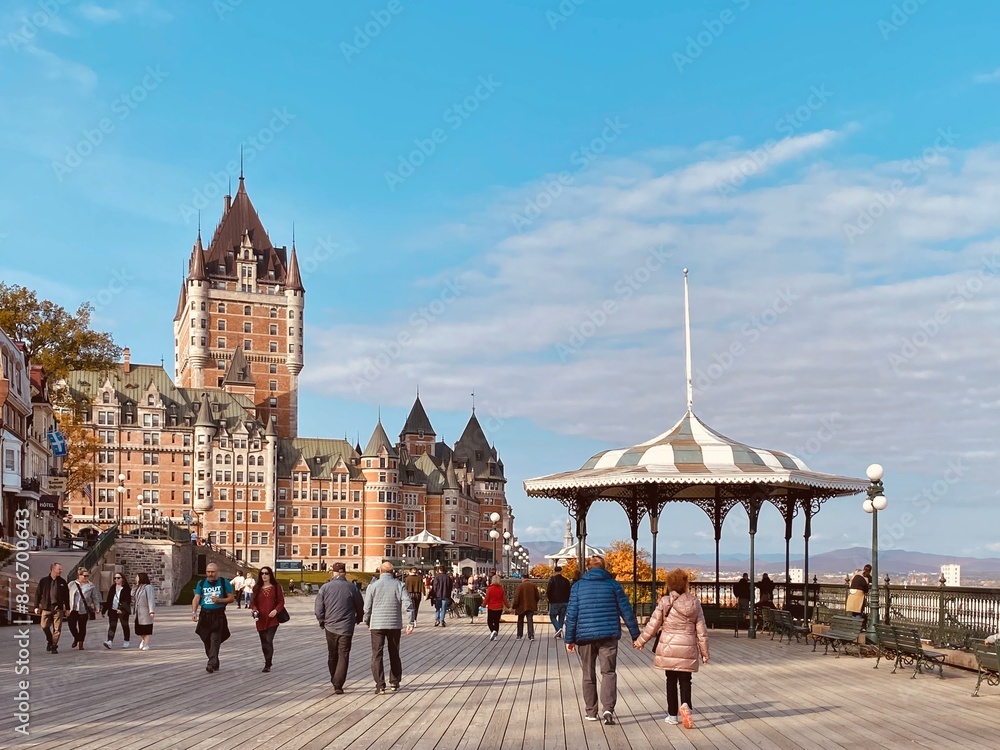 Obraz premium Pier with people strolling by a carousel and grand castle in Quebec City