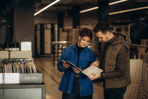 Valokuva Beautiful young couple choosing big granite tiles for their house repairment in
