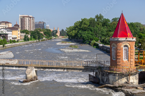 A river in a mountainous region with side barriers for flood protection. The Terek River in the city of Vladikavkaz. A bridge across the river. The river passes through the city. photo