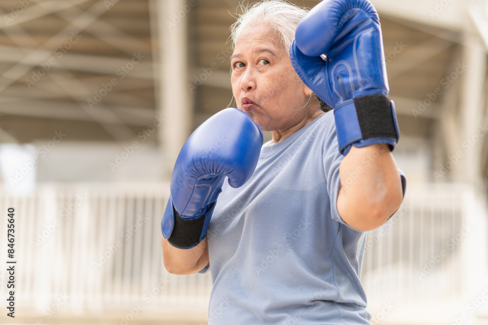 Asian senior sportswoman boxing while working out on parking outdoors Asian senior sportswoman boxing while working out on parking outdoors