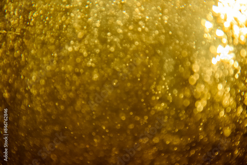 Abstract blurred golden glitter texture with sparkling bokeh lights creating a festive and luxurious background, ideal for holiday and celebration themes. © pandaclub23
