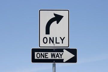 Right turn only and One Way road signs isolated against a blue sky background.