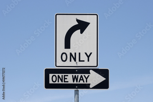 Right turn only and One Way road signs isolated against a blue sky background.