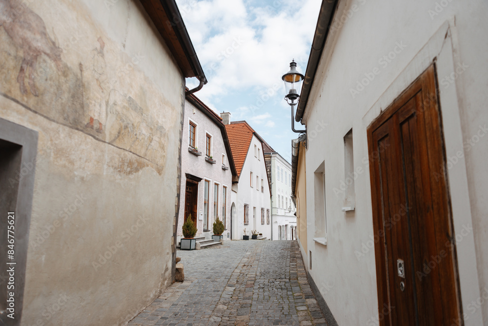 Fototapeta premium The European alley has cobblestones, vintage buildings, and clear skies, creating a charming and historic setting