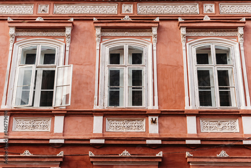 Close-up of a pink historic European building facade with three arched windows and intricate designs. photo