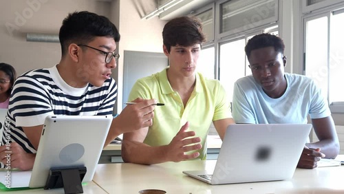 Group of diverse male college students working with a laptop as a team in class