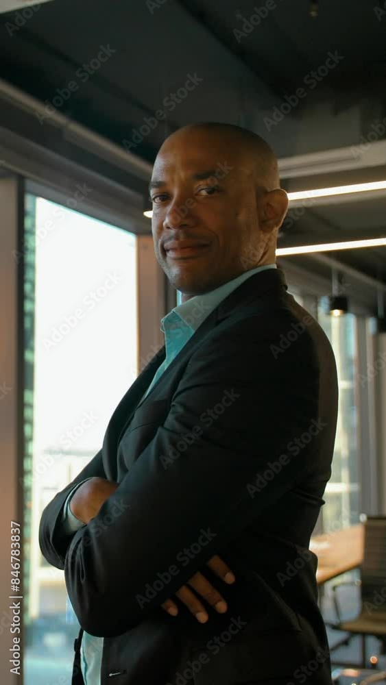 Aframerican entrepreneur standing near huge modern office window with serious expression. Business district background. 4k UHD glidetrack portrait shot. Vertical shot. Aframerican entrepreneur standing near huge modern office window with serious expression. Business district background. 4k UHD glidetrack portrait shot. Vertical shot.