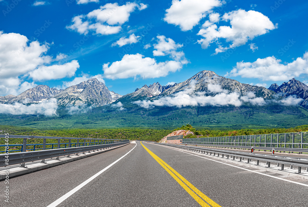 Fototapeta premium Country road with rocky mountains in the background.