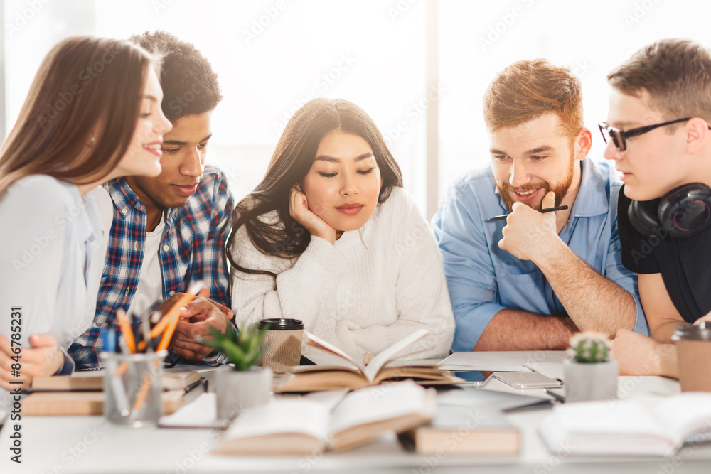Multiracial students at a library table use books to enhance their learning. The group's dynamic interaction embodies a modern, inclusive educational environment. Multiracial students at a library table use books to enhance their learning. The group's dynamic interaction embodies a modern, inclusive educational environment.