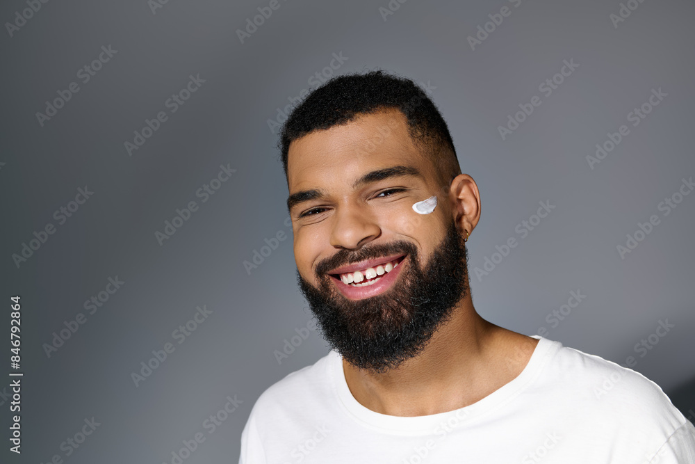 Handsome man with beard tending to his skin in a white tee. Handsome man with beard tending to his skin in a white tee.