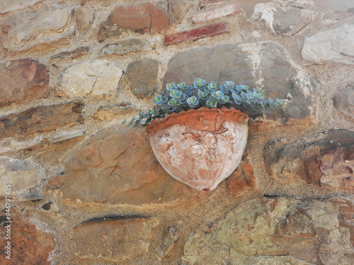 characteristic small terracotta vase on the stone wall in a village