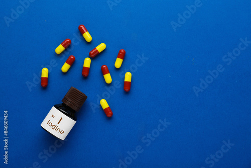 Bottle and iodine pills on blue background, flat lay. Space for text photo