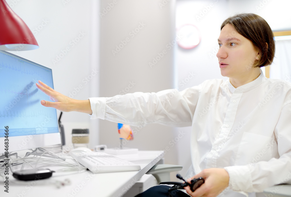 A cardiologist during appointment of patient. Doctor shows EKG on the screen of computer and explains about deviations of heart work. Cardiology consultation and treatment A cardiologist during appointment of patient. Doctor shows EKG on the screen of computer and explains about deviations of heart work. Cardiology consultation and treatment