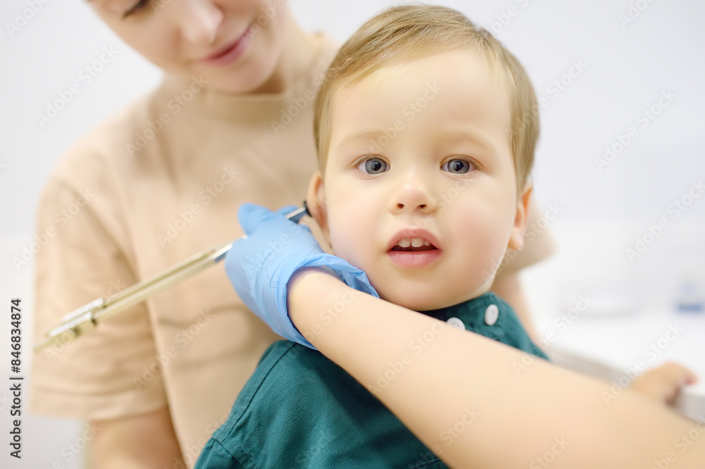 Baby and his mother are being seen by a pediatric neurologist in medical clinic. Doctor conducts tests, checks the reflexes, hearing of small patient using tuning fork. Highly qualified cure Baby and his mother are being seen by a pediatric neurologist in medical clinic. Doctor conducts tests, checks the reflexes, hearing of small patient using tuning fork. Highly qualified cure