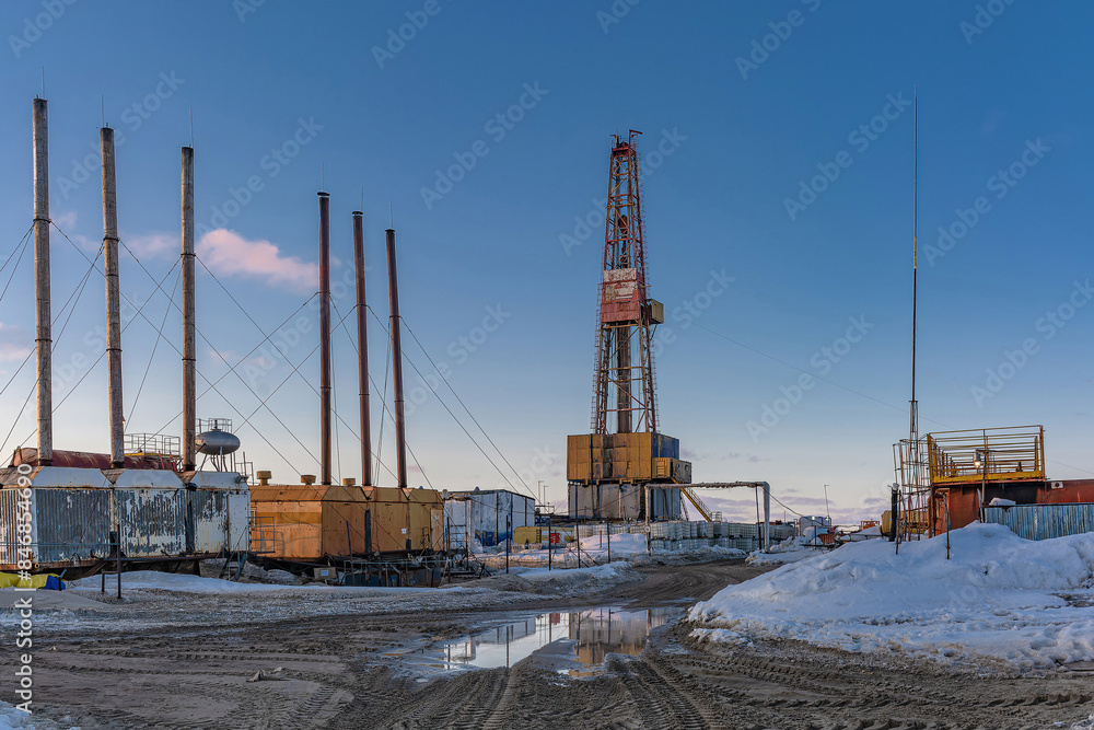 Obraz premium Infrastructure of a drilling rig in an Arctic oil and gas field. Northern snowy winter. Polar day. Blue sky