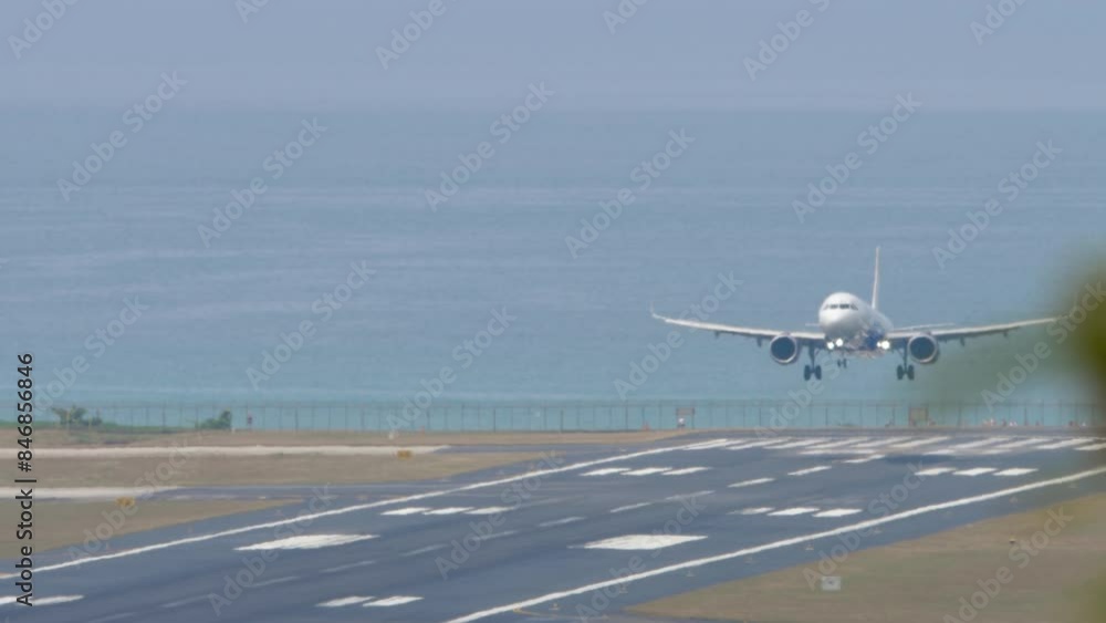 Front view of a jet commercial plane is landing, touching runway and braking. Flight is arriving. Spoilers up