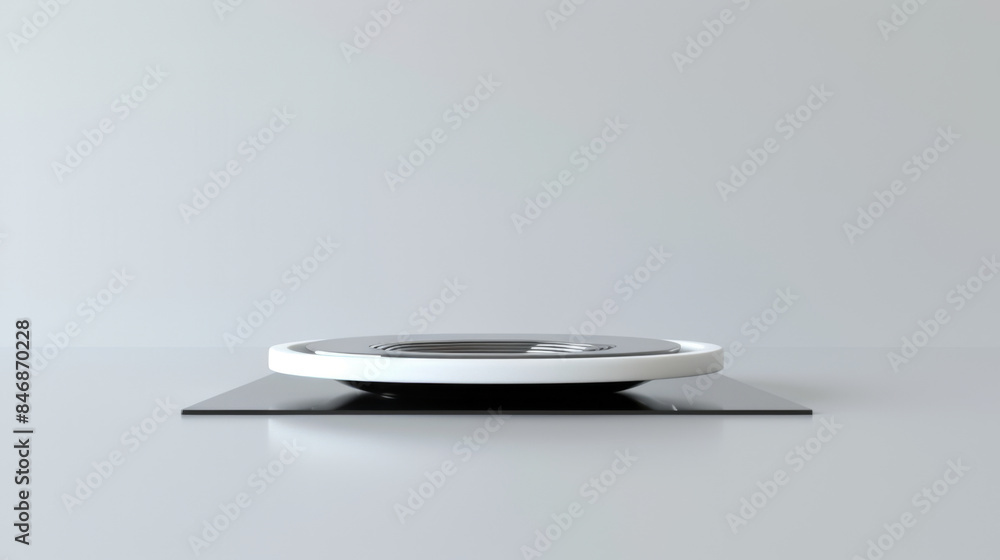 A minimalist, modern turntable with a white top and black base, placed on a grey surface, viewed from a low angle. A minimalist, modern turntable with a white top and black base, placed on a grey surface, viewed from a low angle.