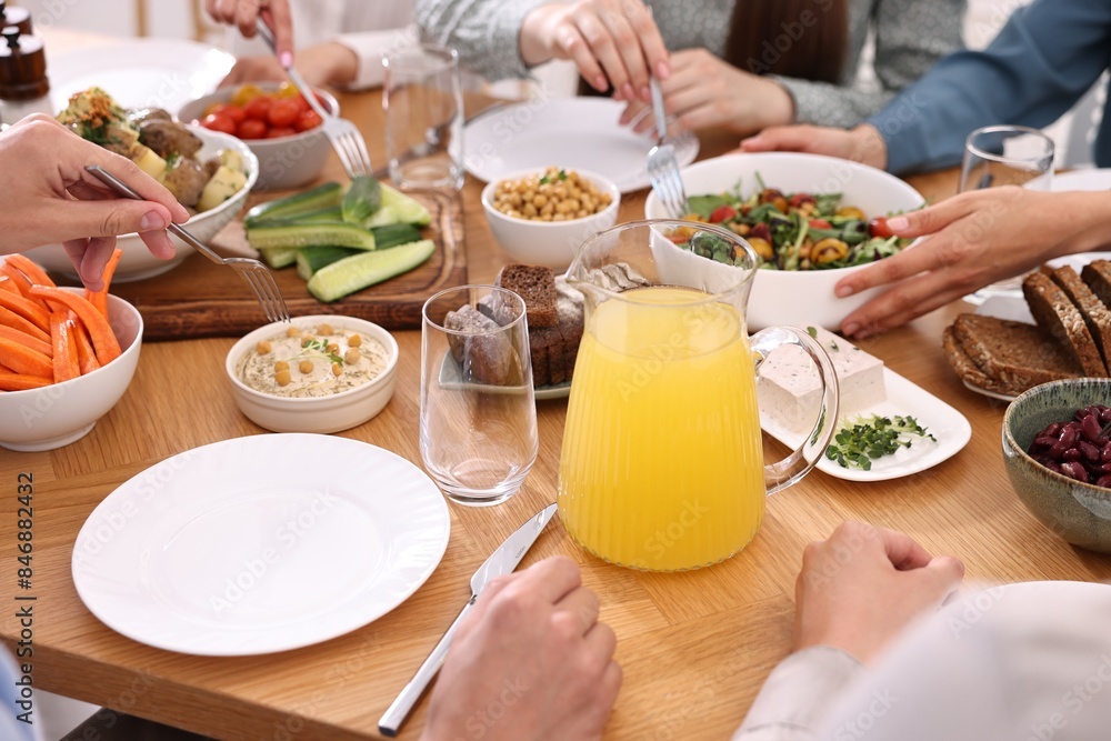 Friends eating vegetarian food at wooden table indoors, closeup Friends eating vegetarian food at wooden table indoors, closeup