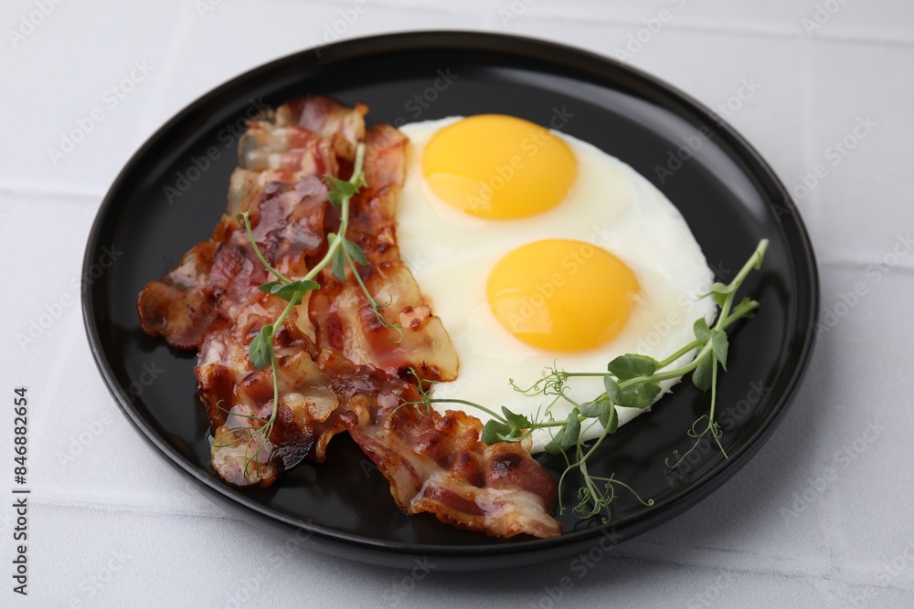 Fried eggs, bacon and microgreens on white tiled table Fried eggs, bacon and microgreens on white tiled table