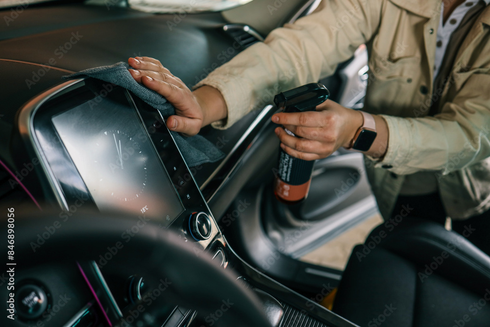 Naklejka premium A woman at a car wash does a full dry-cleaning of all parts of a car using special chemistry, cloths, sponges and brushes. Concept of: Full car cleaning, Dry cleaning, Professional service. Car, Work