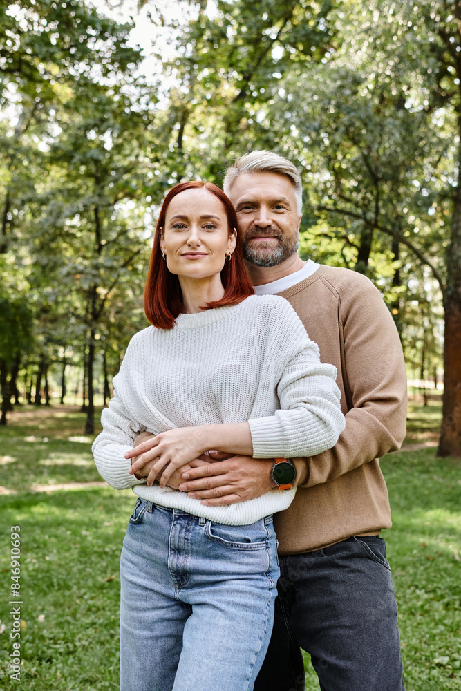 Adult couple in casual attire standing together in a park. Adult couple in casual attire standing together in a park.