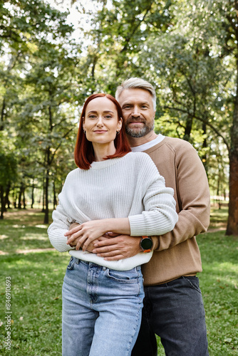 Adult couple in casual attire standing together in a park. © LIGHTFIELD STUDIOS