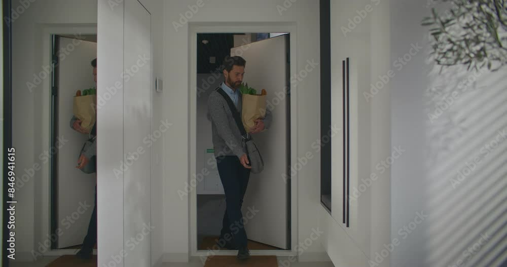 Handsome Caucasian male with beard entering home after work. buying groceries after leaving work. Going shopping before coming back to apartment. Happy man preparing to cook. Smiling with joy. Handsome Caucasian male with beard entering home after work. buying groceries after leaving work. Going shopping before coming back to apartment. Happy man preparing to cook. Smiling with joy.