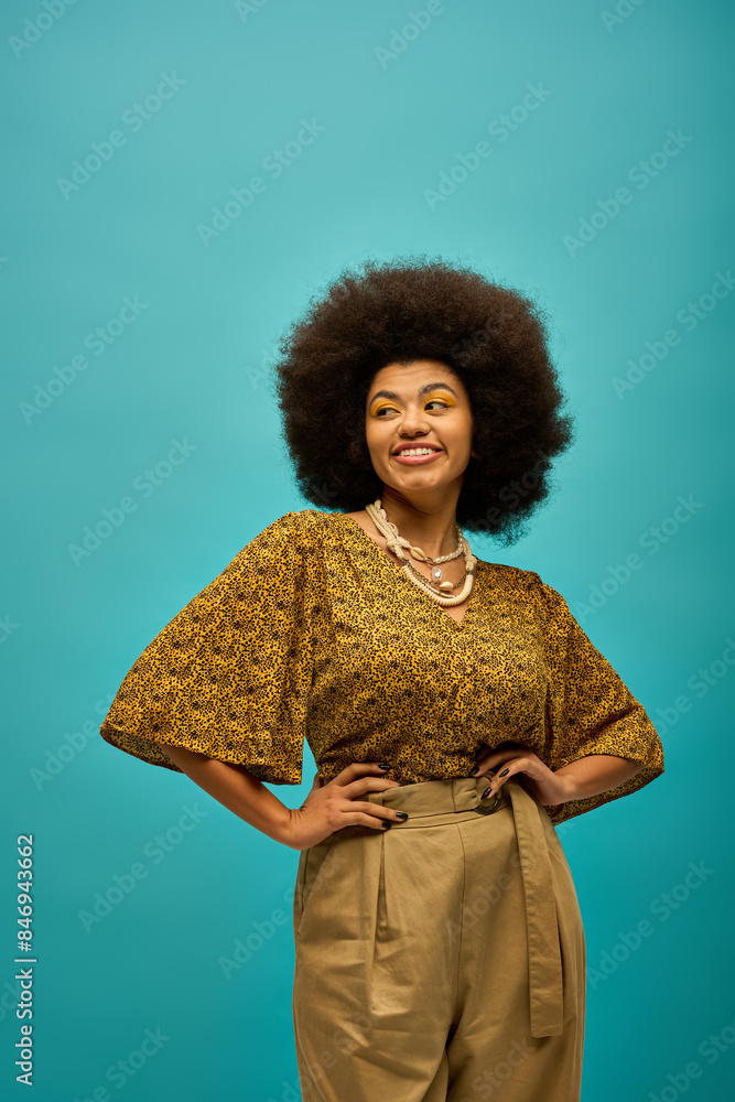 Stylish African American woman with curly hairdohair standing in front of vibrant blue backdrop. Stylish African American woman with curly hairdohair standing in front of vibrant blue backdrop.