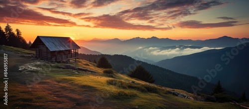 Fototapeta Naklejka Na Ścianę i Meble -  Wooden house perched on a mountain slope with a scenic sunset in the background. with copy space image. Place for adding text or design
