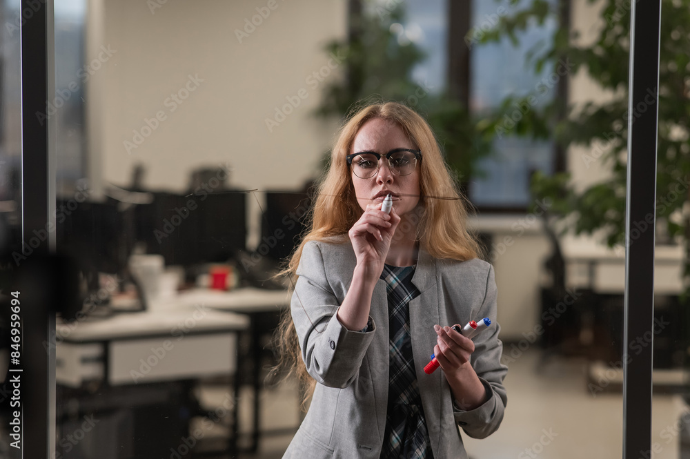 Caucasian woman writing pyramid diagram with questions on glass wall. Caucasian woman writing pyramid diagram with questions on glass wall.