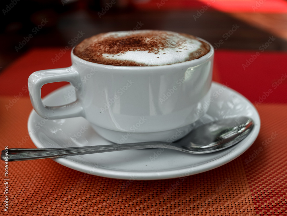 Fototapeta premium a cup of coffee in a white cup on an orange table. day.the sun. blurred background