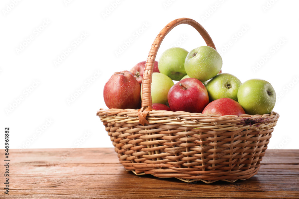 Fresh red and green apples in wicker basket on wooden table against white background. Space for text Fresh red and green apples in wicker basket on wooden table against white background. Space for text