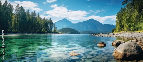Tranquil lake framed by rocks and verdant trees under a clear blue sky. with copy space image. Place for adding text or design