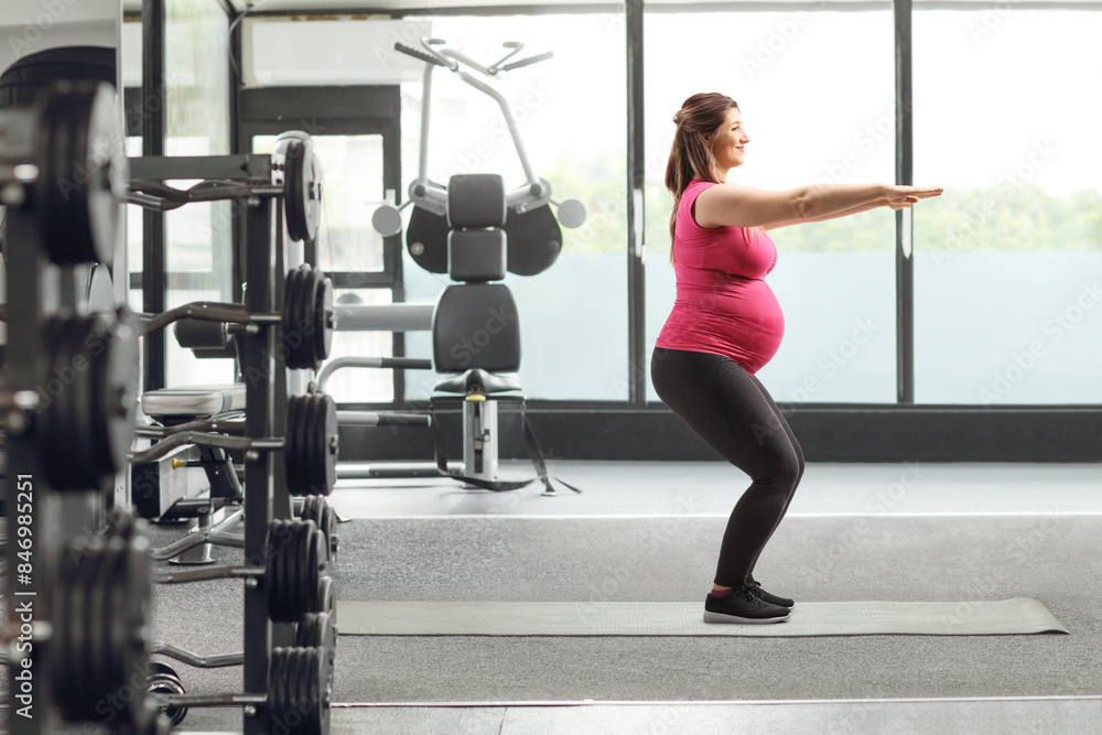 Pregnant woman exercising squats at a gym Pregnant woman exercising squats at a gym