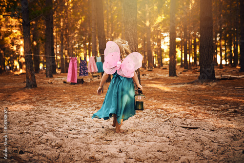 Back, walking and child in forest, girl and wings of butterfly, lantern and journey in morning. Fairytale, kid and travel in woods, trees and nature of California, summer and adventure of outdoor
